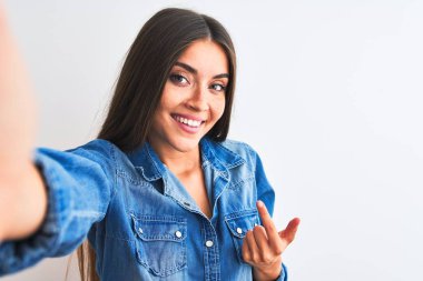 Kot gömlek giyen güzel bir kadın kamerayla selfie çekiyor. İzole edilmiş beyaz arka planda. Gel buraya.
