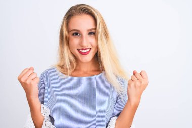 Zarif mavi tişört giyen genç güzel bir kadın izole edilmiş beyaz arka planda durup gururla bağırıyor ve zaferi ve başarıyı kutluyor. Çok heyecanlı, coşkulu bir duygu.