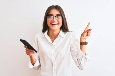 Gözlük takan güzel bir iş kadını izole edilmiş beyaz arka plan üzerinde akıllı telefon kullanıyor.