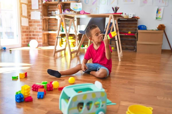 愛らしい幼児は幼稚園でおもちゃの多くの周りにブロックを構築して遊んでいます — ストック写真