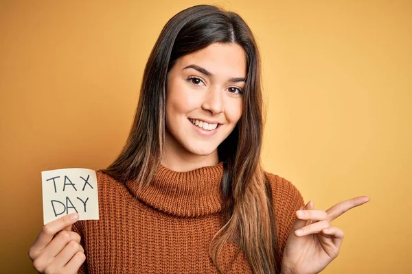 Junges Schönes Mädchen Hält Mahnzettel Mit Steuertagsmeldung Über Gelbem Hintergrund — Stockfoto