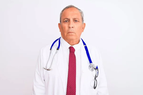 年长白发苍苍的医生男子戴着听诊器站在孤立的白色背景上 脸上表情严肃 简单自然地看着相机 — 图库照片