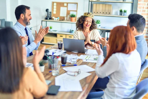 Group of business workers smiling happy and confident. Working together with smile on face applauding one of them wearing king crown at the office