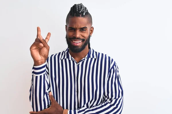 African american man with braids wearing striped shirt over isolated white background smiling with happy face winking at the camera doing victory sign. Number two.