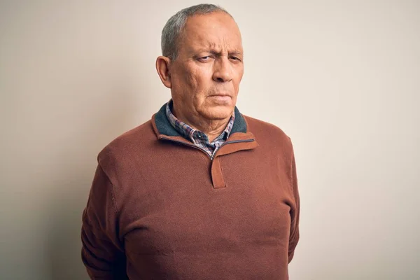 Senior handsome man  wearing elegant sweater standing over isolated white background skeptic and nervous, frowning upset because of problem. Negative person.
