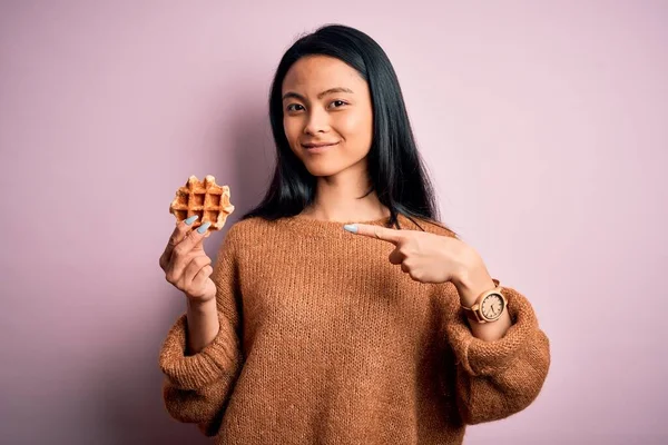 Young Beautiful Chinese Woman Holding Waffle Standing Isolated Pink Background — Stok fotoğraf