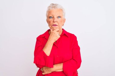 İzole edilmiş beyaz arka planda kırmızı tişört giyen yaşlı, gri saçlı kadın kameraya kollarını kavuşturup gülümseyerek ve çenesini kaldırarak bakıyor. Olumlu düşünüyorum..