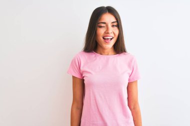 Pembe günlük tişört giyen genç güzel bir kadın izole edilmiş beyaz arka planda duruyor kameraya seksi bir ifadeyle bakıyor, neşeli ve mutlu bir yüzle..
