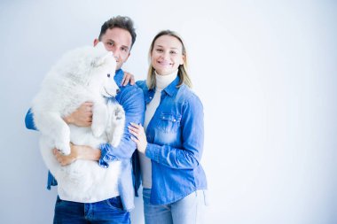 Genç güzel çift izole beyaz arka plan üzerinde duran köpek tutarak