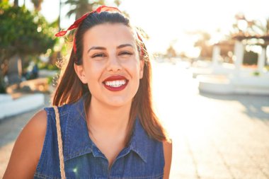 Genç, güzel bir kadın mutlu bir şekilde gülümsüyor. Güneşli bir yaz gününde Tenerife, Puerto de la Cruz sokaklarında yürüyor.