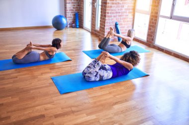Genç ve güzel bir grup sporcu kadın yoga yapıyor. Eğilip spor salonunda poz vermek.