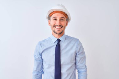 Young business man wearing contractor safety helmet over isolated background with a happy and cool smile on face. Lucky person.