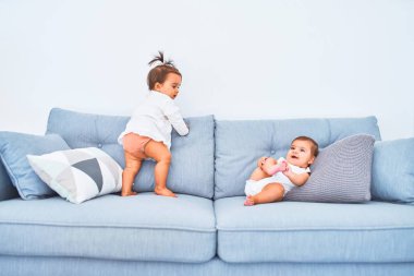 Güzel bebek mutlu kızlar, ana okulunda kanepede birlikte oynuyorlar.