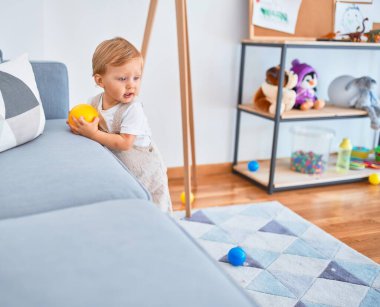 Sevimli sarışın çocuk anaokulunda bir sürü oyuncakla oynuyor.