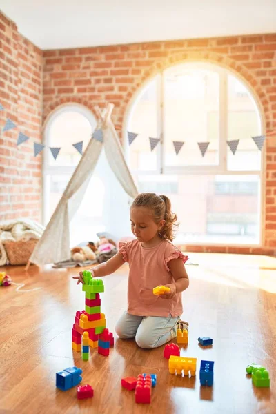 Schöne Blonde Kleinkind Mädchen Spielt Mit Plastikklötzen Einen Turm Kindergarten — Stockfoto