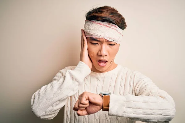 Young handsome chinese man injured for accident wearing bandage and strips on head Looking at the watch time worried, afraid of getting late