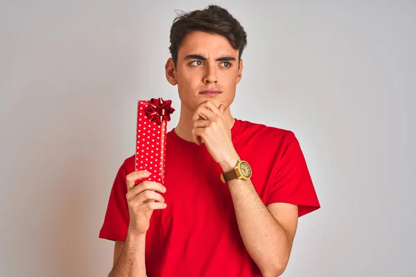 Teenager Boy Holding Birthday Gift Isolated Background Serious Face Thinking — Stok fotoğraf