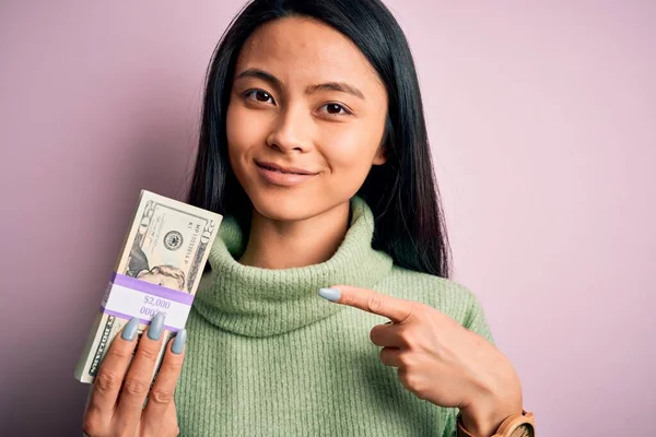 Young Beautiful Chinese Woman Holding Dollars Standing Isolated Pink Background — 스톡 사진