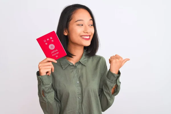 日本のパスポートを持った美しい中国人女性が白地を指差して親指を立てて笑顔で横に見せます — ストック写真