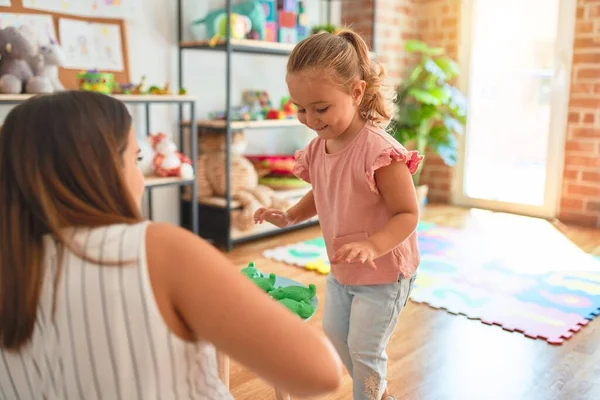 美しいです先生とブロンド学生幼児女の子遊びますとともにプラスチックカエルおもちゃで幼稚園 — ストック写真