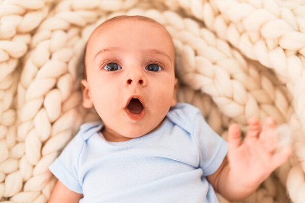 Adorable baby lying down over blanket on the sofa at home. Newborn relaxing and resting comfortable