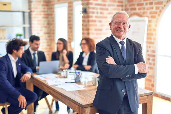 Group of business workers smiling happy and confident working together in a meeting. One of them, standing with smile on face looking at camera at the office.