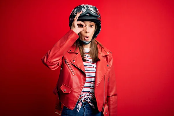 若い美しいブルネットのオートバイのヘルメットと赤いジャケットを身に着けているオートバイの女性は 驚きの顔でショックを受けたOkジェスチャーを行う 指を通して見て目 不信仰の表現 — ストック写真