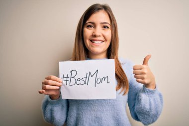 Elinde en iyi anne mesajı olan genç ve güzel bir kadın anneler gününü büyük bir gülümsemeyle kutluyor.