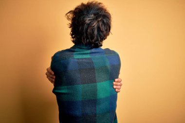 Young handsome man wearing casual shirt standing over isolated yellow background Hugging oneself happy and positive from backwards. Self love and self care