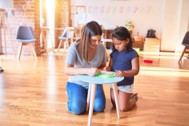 Güzel öğretmen ve küçük kız anaokulunda dijital tahta kullanarak resim çiziyor.