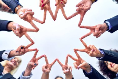 Bir grup işçi ofiste parmaklarıyla sembol çiziyor.