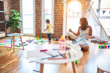 Anaokulunda renkli toplarla oynayan genç ve güzel bir öğretmen ve çocuk.