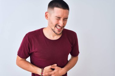 Genç ve yakışıklı bir adam midesi üzerinde el üstünde duruyor çünkü hazımsızlık, acı verici bir hastalık kendini iyi hissetmiyor. Ache kavramı.