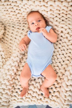 Evdeki battaniyenin üzerinde kanepeye uzanmış sevimli bir bebek. Yeni doğmuş bebek rahatlıyor ve dinleniyor.