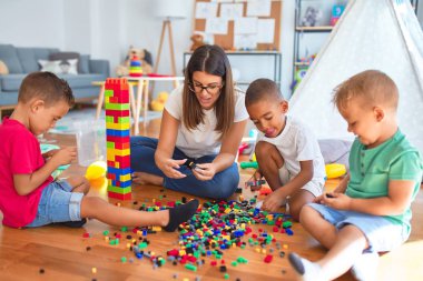 Anaokulundaki bir sürü oyuncağın etrafına taş döşeyen genç ve güzel öğretmenler ve yeni yürümeye başlayan çocuklar.