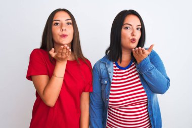 İzole edilmiş beyaz arka planda dikilmiş sıradan kıyafetler giyen genç ve güzel kadınlar havayla öpüşürken kameraya bakıyorlar. Güzel ve seksi. Aşk ifadesi.