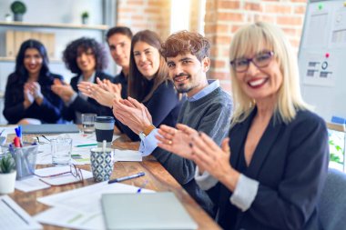 Bir grup iş adamı mutlu ve kendinden emin gülümsüyor. Birlikte çalışırken yüzümüzde gülümsemeyle kameraya bakıp ofisi alkışlıyorduk.