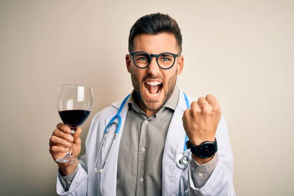 孤立した背景に新鮮なワインのグラスを飲み聴診器を身に着けている若い医者の男はいらいらし 怒りで叫び 狂気と大声で手を上げ 怒りの概念 — ストック写真
