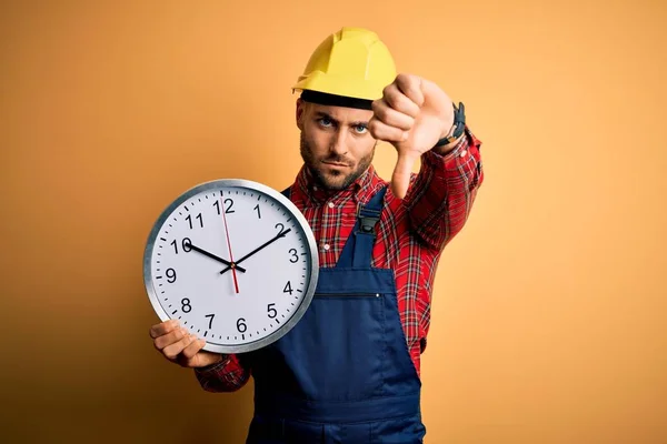 Junger Bauarbeiter Mit Schutzhelm Große Uhr Vor Gelbem Hintergrund Mit — Stockfoto