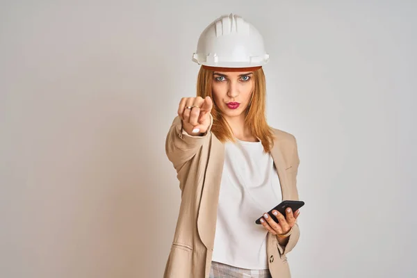 年轻的高加索工程师女人用智能手机 头戴安全帽 用手指着相机和你 正面积极自信的手势 — 图库照片