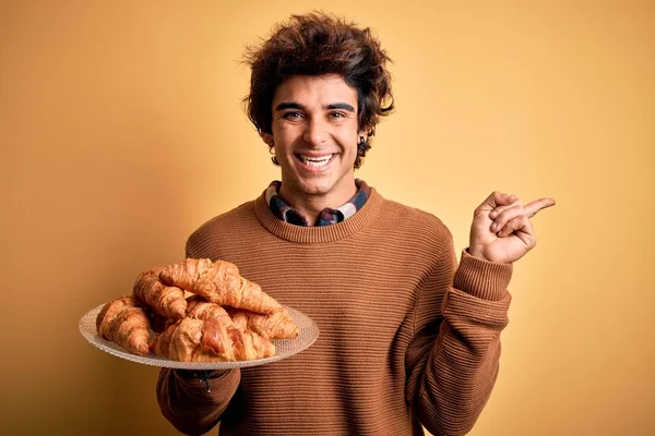 Mladý Pohledný Muž Držící Talíř Croissanty Stojící Nad Izolovaným Žlutým — Stock fotografie