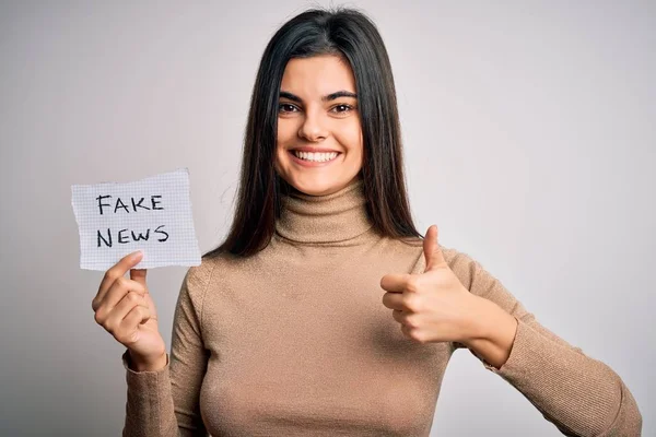 Mladá Krásná Brunetka Žena Drží Papír Falešnou Zprávou Bílém Pozadí — Stock fotografie