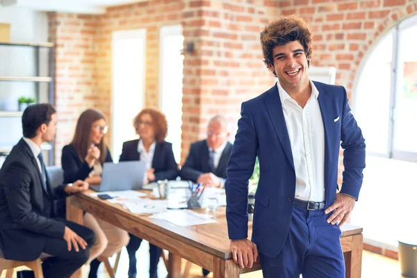 Group of business workers smiling happy and confident working together in a meeting. One of them, standing with smile on face looking at camera at the office.