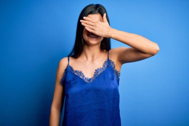 Zarif ve rahat mavi iç çamaşırı giyen genç, güzel esmer kadın. Gülümseyen ve gülen elleri yüzünde, şaşırtmak için gözleri örtüyor. Kör kavram.