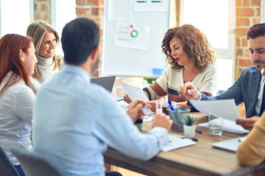 Birlikte çalışan bir grup işçi. Ofiste dizüstü bilgisayarla oturup belgeleri okumak.