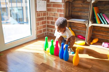 Beautiful african american toddler playing bowling at kindergarten clipart