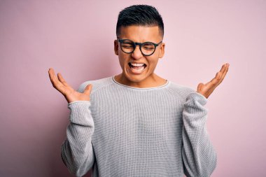 Pembe arka plan üzerine gündelik süveter ve gözlük takan genç, yakışıklı Latin adam kollarını kaldırıp heyecanla haykırarak başarının çılgınlığını kutluyor. Kazanan konsept