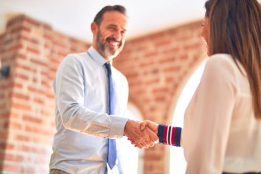 Mutlu ve kendinden emin gülümseyen iki orta yaşlı iş adamı. Yüzünde bir gülümsemeyle ofiste el sallayarak çalışmak.