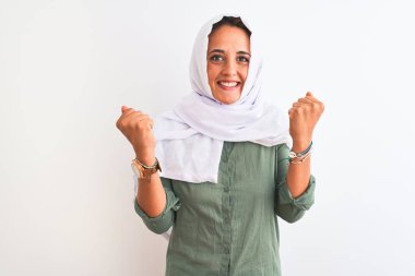 Geleneksel Müslüman tesettüre bürünmüş genç, güzel bir Arap kadın kollarını kaldırarak ve açık gözlerle başarıyı kutluyor ve şaşırıyor. Kazanan konsept.