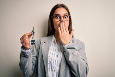 Genç, güzel esmer ev temsilcisi kadın evinin anahtarını beyaz arka planda tutuyor. Ağzı kapalı. Yanlışlıkla utancından ağzı açık kalmış, korku ifadesi, sessizlikten korkmak, gizli bir kavram.